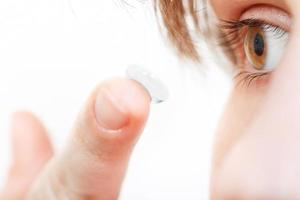 girl inserts contact lens in eye photo