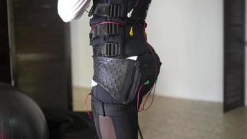 Young woman wears electrodes suit for physical therapy video