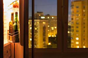 Open refrigerator with bottles in night photo