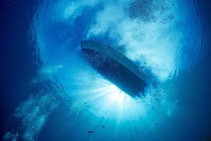 boat ship from underwater blue ocean with sun rays photo