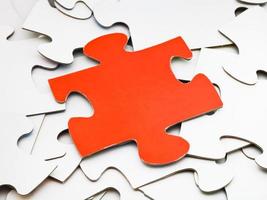 separate red piece on pile of white jigsaw puzzles photo