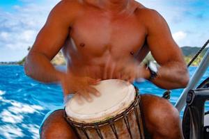 bora bora hombre polinesio tocando tambor en barco foto