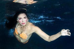 sirena nadando bajo el agua en el mar azul profundo foto