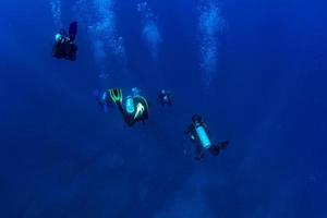 Scuba diver underwater in the deep blye ocean abyss photo