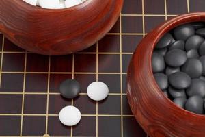 juego de go en blanco y negro, piedras y tazones de madera foto