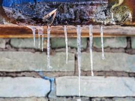 icicles on roof of house with brick wall photo