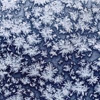 snowflakes and frost on frozen window glass photo