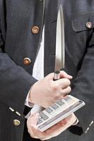 calculadora y cuchillo en manos de un hombre de negocios foto