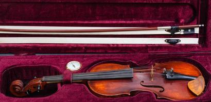 viejo violín con arco en estuche de terciopelo rojo foto
