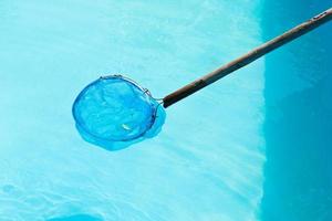 limpieza de piscina exterior con skimmer de hojas de red foto