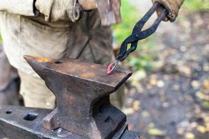 Blacksmith forges a buckle on anvil photo