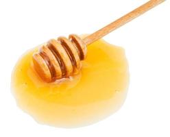 puddle of transparent honey and stick close up photo