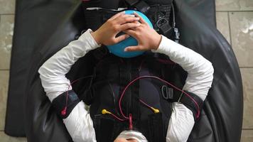 Young woman wears electrodes suit for physical therapy video