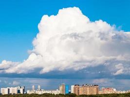 gran nube baja en el cielo azul sobre la ciudad en verano foto