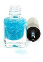 bottle with spilled turquoise nail polish on white photo