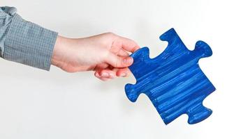 blue painted puzzle piece in female hand photo