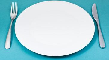 empty white plate with fork and knife set on green photo