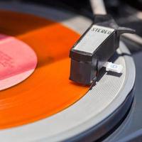 tonearm of turntable on orange vinyl record photo