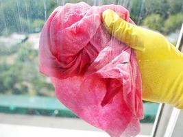 hand in yellow glove cleaning window glass photo