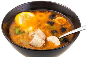 Solyanka fish soup in bowl with spoon close up photo