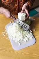 woman shredding cabbage by manual slaw cutter photo