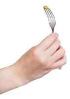 female hand holds fork with impaled green pea photo