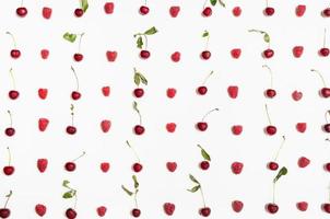 many raspberries and cherries arranged on white photo