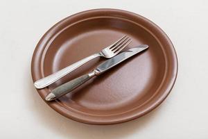 brown plate with parallel knife, spoon on white photo