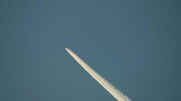 Airplane with trail against the blue sky. Concept for travelling, flying, leaving things behind, moving forward, freedom, moving on, travel the world video