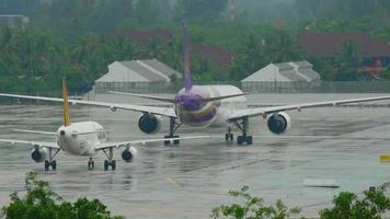 phuket, thailand 2. dezember 2016 - tigerair airbus 320 9v tar rollt nach der landung, thai airways boeing 777 hs tkd namens thepali rollt vor dem abflug. regnerisches Wetter video