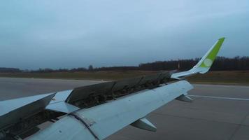 Airplane wing with open flaps. Looking through plane window. Landing process video