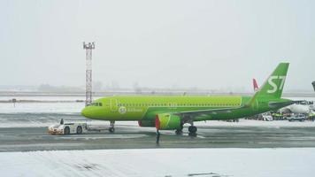 NOVOSIBIRSK, RUSSIAN FEDERATION November 15, 2020 - S7 Airlines Airbus A320 with covered engines being towed by tug truck for maintenace. video