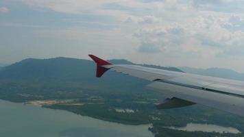 das flugzeug, das vor der landung des flughafens von phuket absteigt, blick aus dem flugzeug-bullauge. video