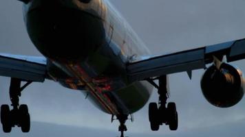 The wide bodied aircraft lands on the illuminated runway in the early morning video