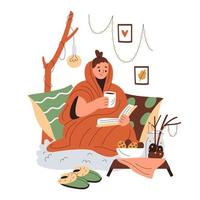 Smiling girl wrapped in a blanket sits in cushions and reads, holding a cup of warm drink vector