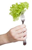 hand holds fork with impaled fresh leaf lettuce photo