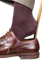 man puts on brown shoe with shoehorn isolated photo