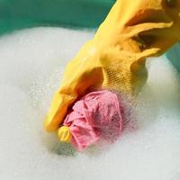 hand in yellow rubber glove rinsing wet duster photo