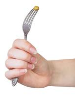 hand holding dinning fork with impaled green pea photo