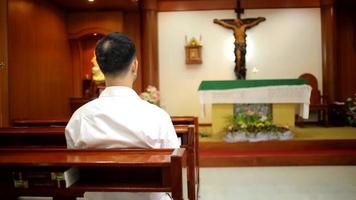 barba de homem asiático vestindo com camisa cristã orando orando a Deus enquanto está sentado na igreja. video