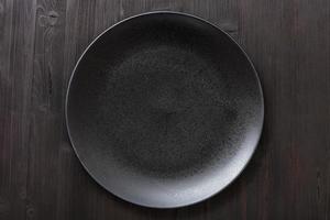 top view of black plate on dark brown table photo