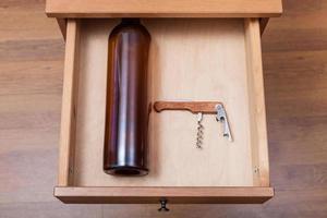 empty wine bottle and corkscrew in open drawer photo