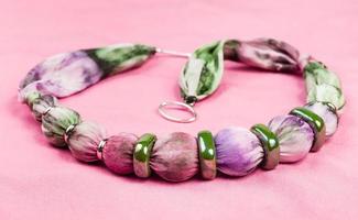 necklace from silk balls and ceramic rings on pink photo