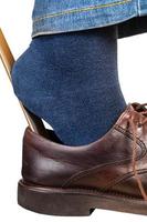 man puts on brown shoes using shoe horn close up photo