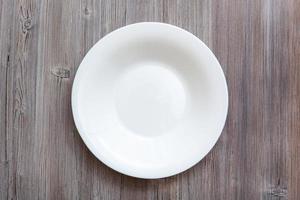 above view of white deep plate on gray brown table photo