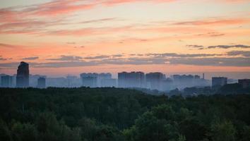 early sunrise and morning mist over woods and city photo