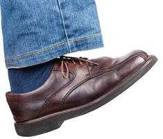 right foot in jeans and brown shoe takes a step photo