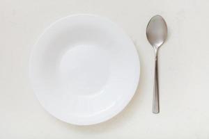 top view of white deep plate and spoon on plaster photo