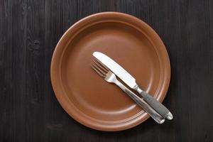 top view of brown plate with flatware on dark photo