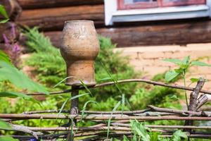 wattle fence with old clay pot and log house photo